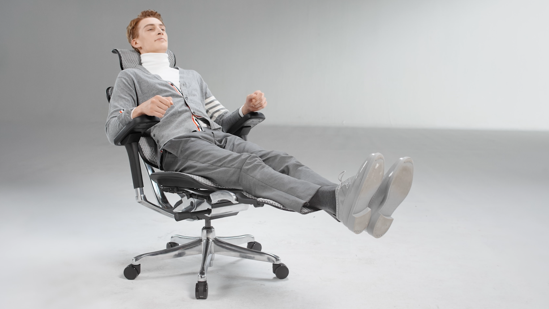 Man wearing grey outfit reclining in his Ergohuman Elite office chair with the legrest out so he can keep his legs elevated