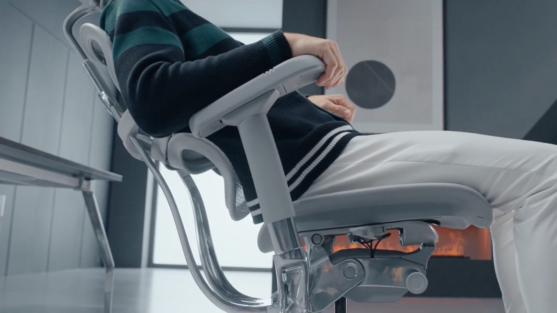 A man sitting in a grey Ergohuman chair is leaning back comfortably. 