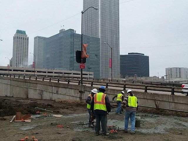 A group of construction workers are working on a bridge in a city.