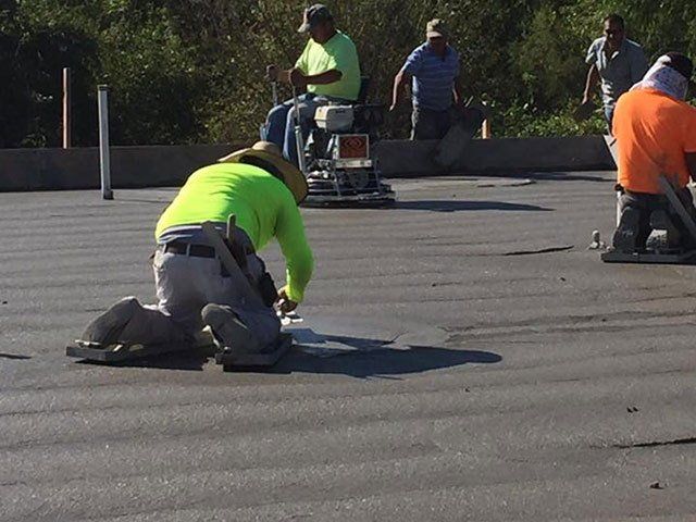 A group of construction workers are working on a concrete surface
