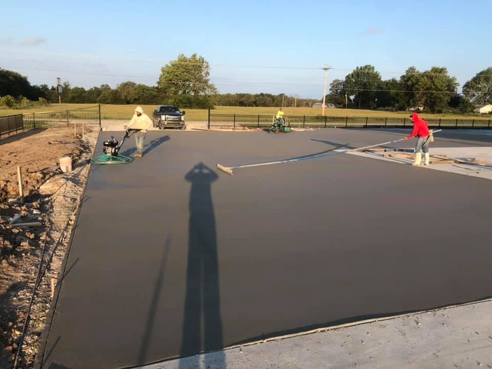 A group of people are working on a concrete driveway. A group of people are working on a concrete driveway.
