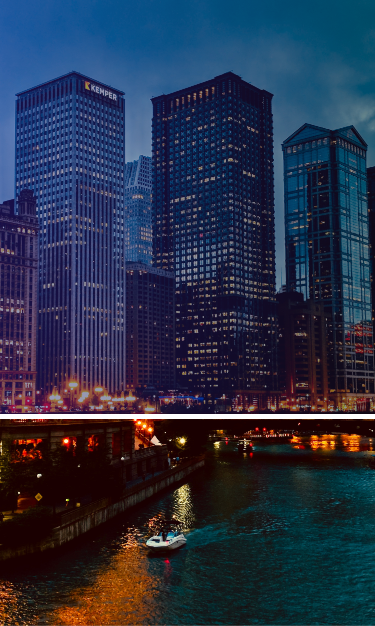 A boat is floating down a river in front of a city skyline at night.