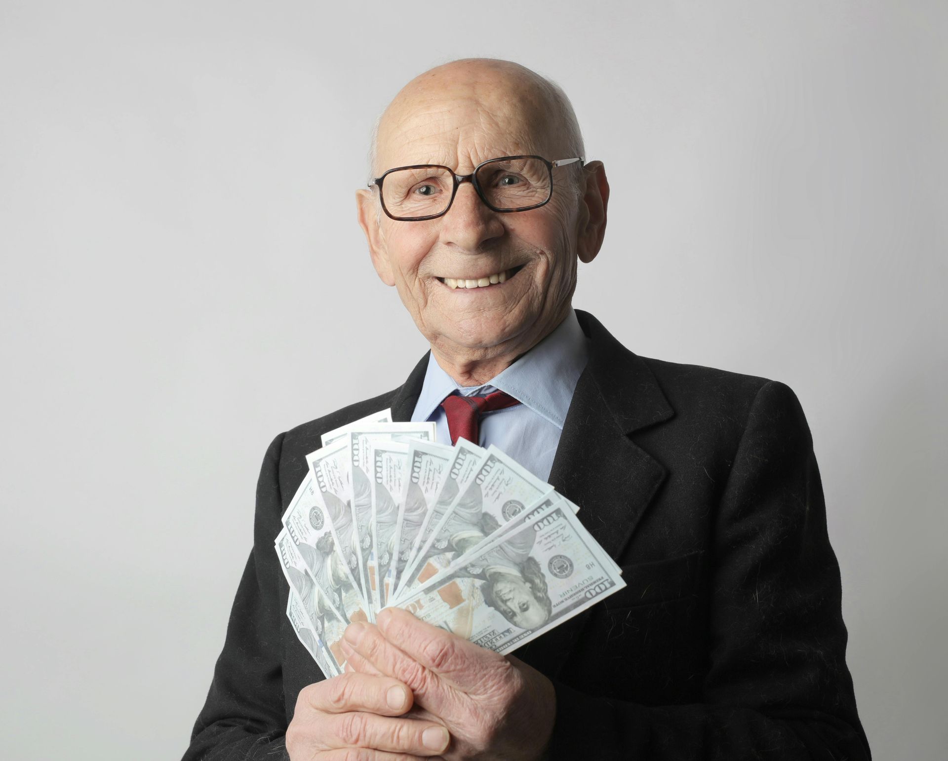 A man in a suit and tie is holding a fan of money.