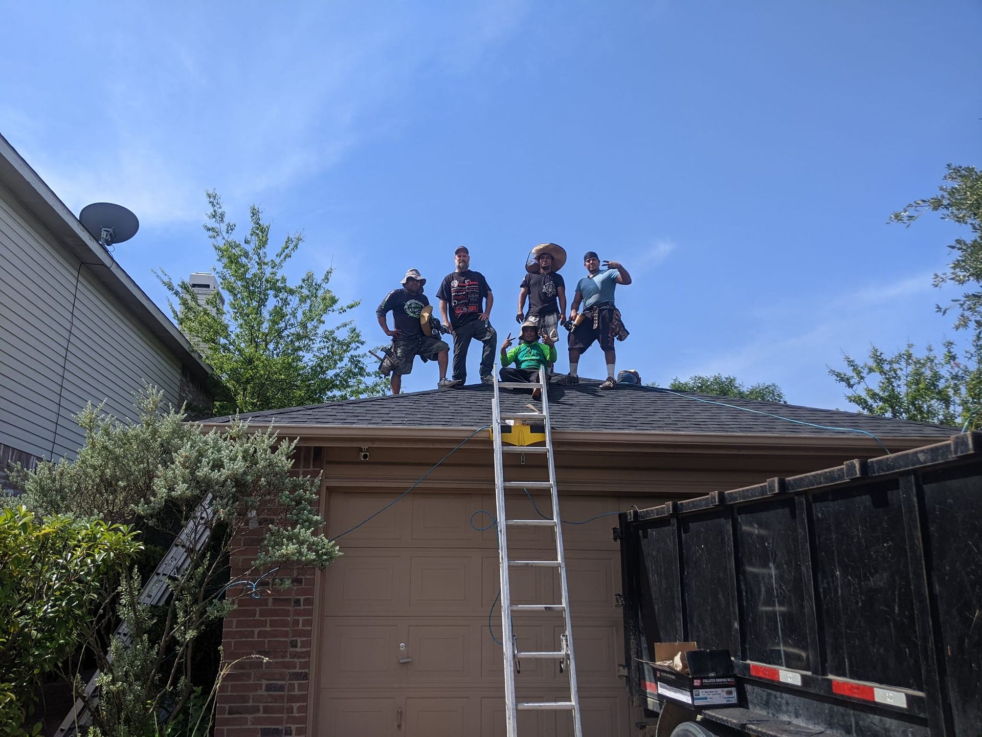 Roofing crew on a garage roof in front of a blue sky.