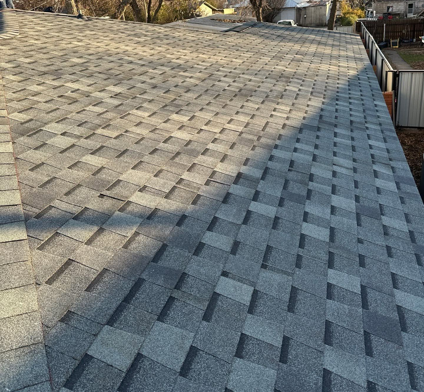 Gray shingled roof with a diagonal shadow, viewed from above.