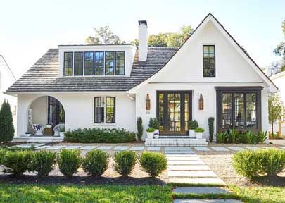 A white house with black windows and a walkway in front of it.