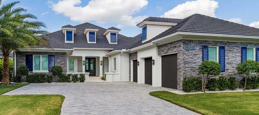 A large house with a driveway and a palm tree in front of it.