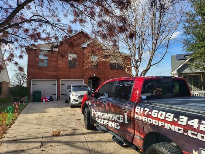 A red truck is parked in front of a brick house.