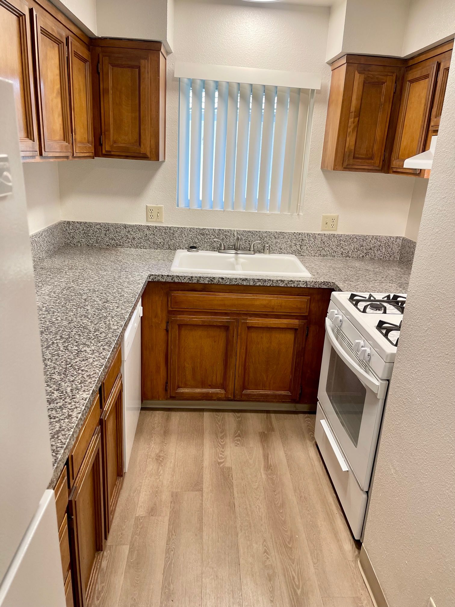 Small kitchen with wood cabinets, gray countertops, and a white stove.