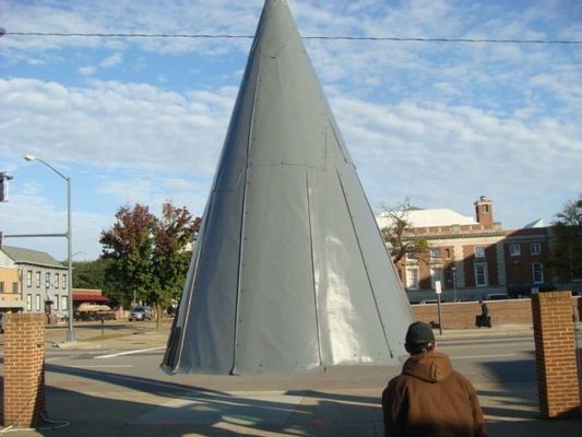 A man stands in front of a large cone shaped structure