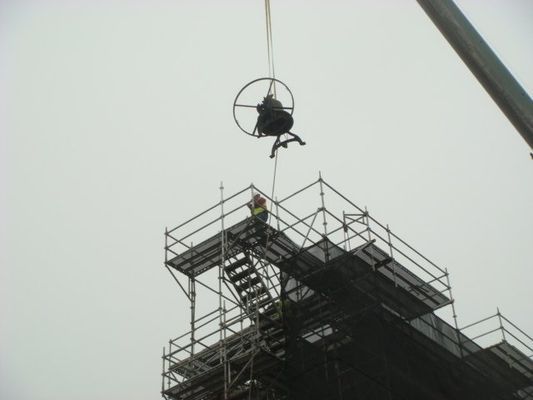 A crane is lifting a bell on top of a building