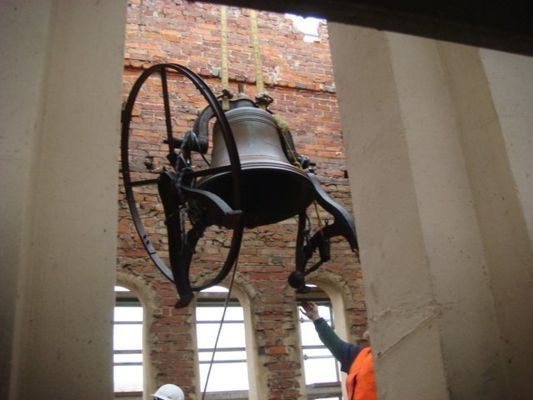 A bell is hanging from the ceiling of a building