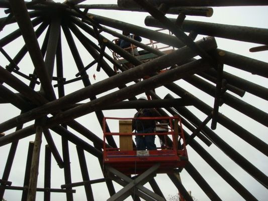 A man on a lift looking up at a ferris wheel