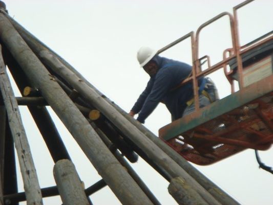 A man wearing a hard hat is working on a crane
