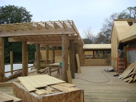 A wooden structure is being built with a ladder in the background