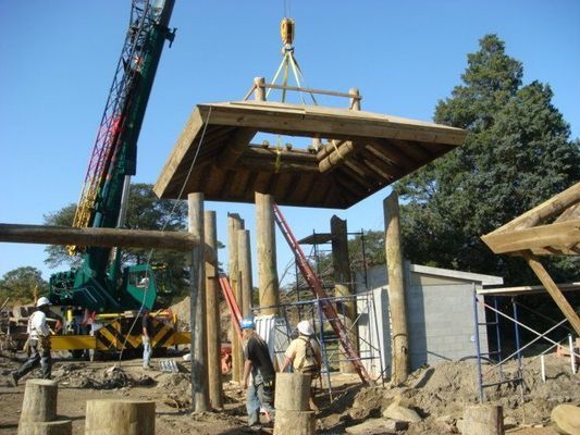 A crane is lifting a wooden structure in the air