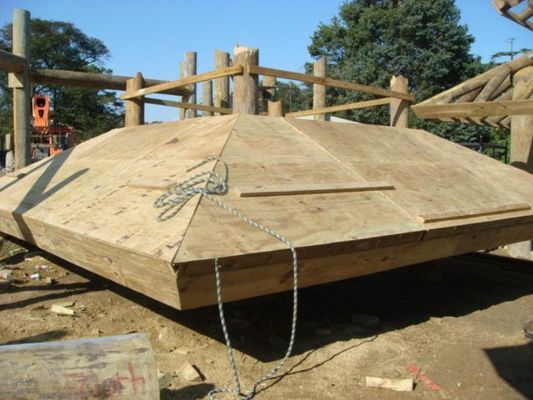 A large wooden structure is being built in the dirt