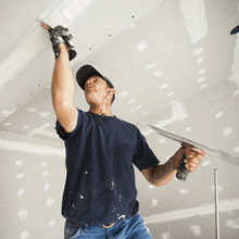 A man is plastering a ceiling with a trowel.