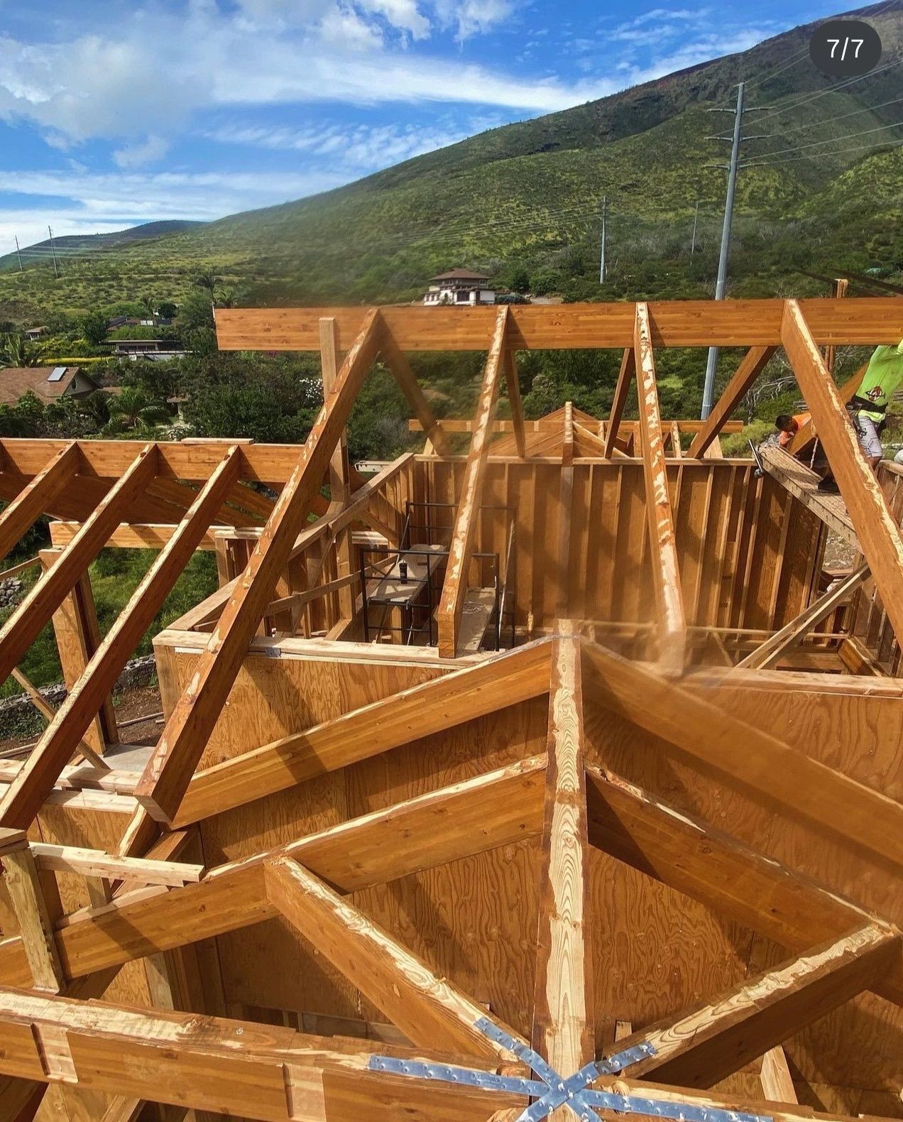 Wooden roof truss framework under construction with mountain and blue sky in the background