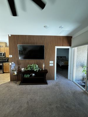 Living room with wall-mounted TV, wooden accent wall, fireplace, and sliding glass doors