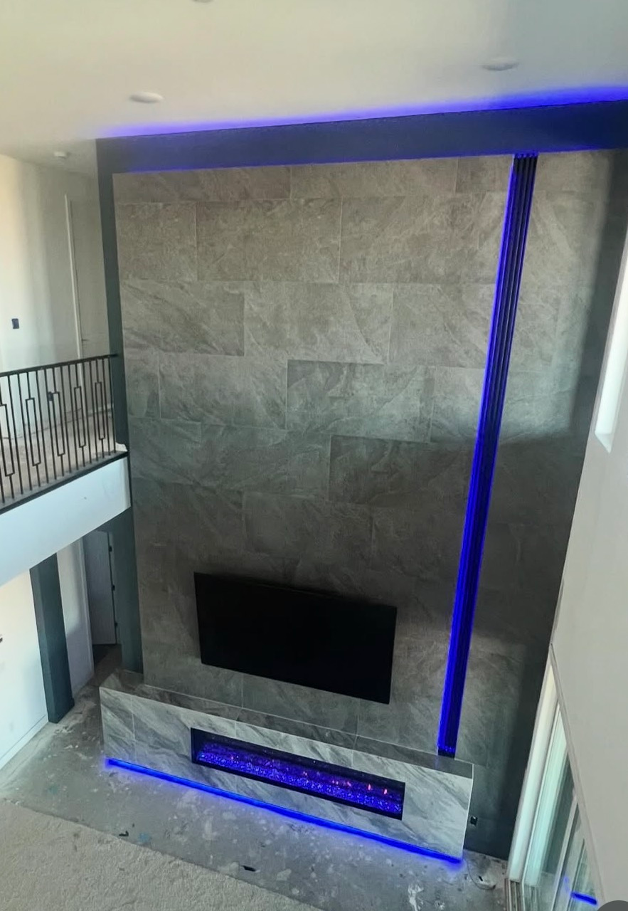 Modern living room with a tall gray stone fireplace and blue LED accent lighting