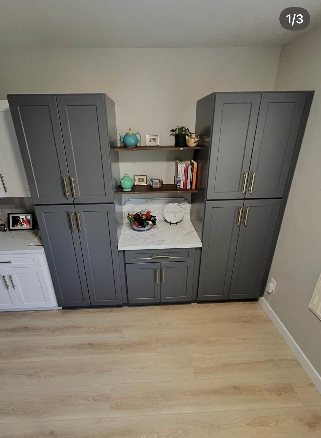 Gray built-in cabinets and shelves against a wall in a room with light wood flooring.