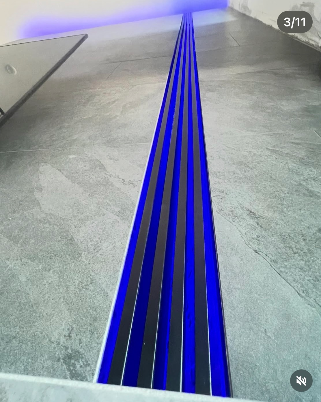 Blue glowing floor lines converge down a gray concrete hallway.