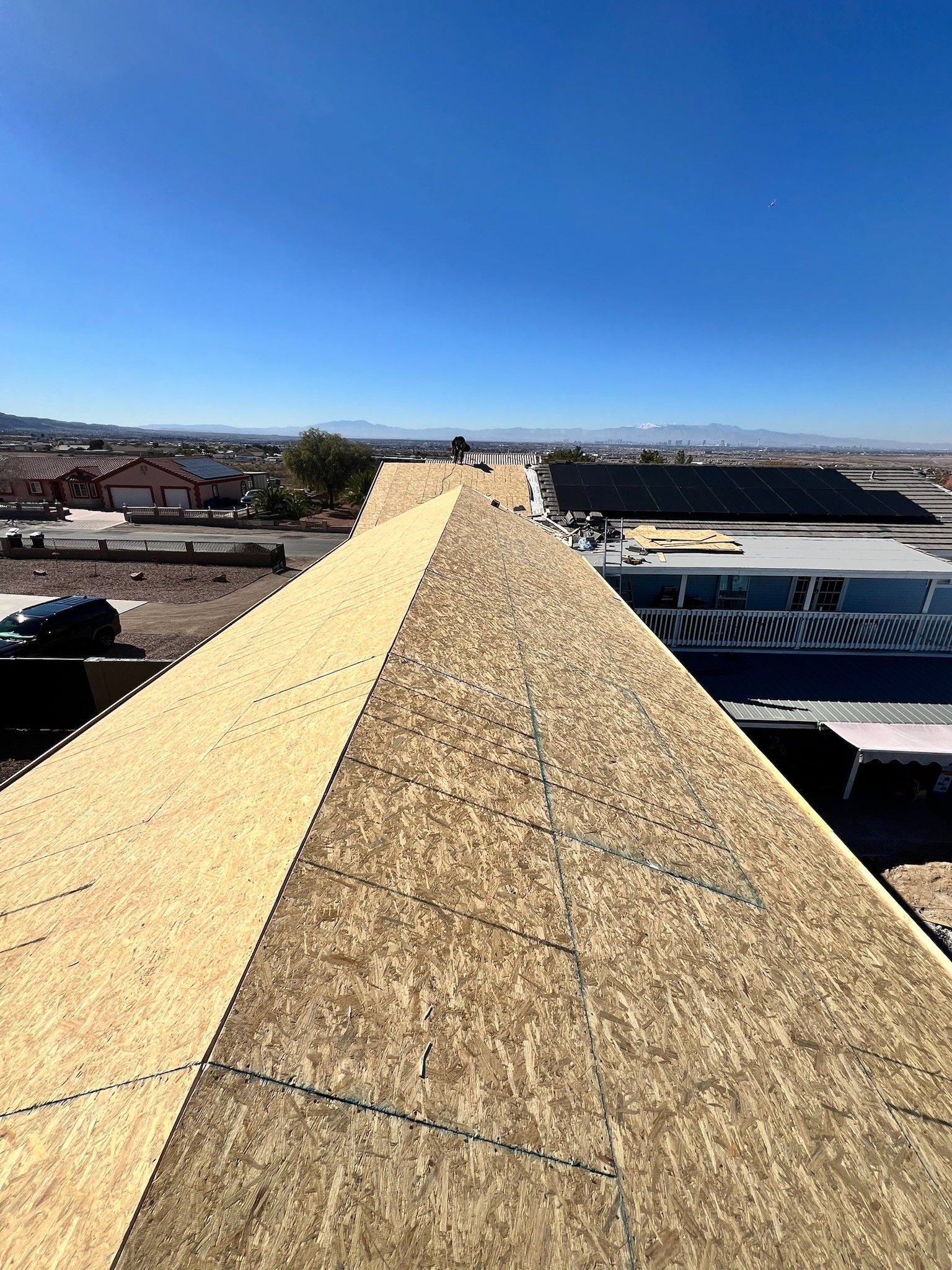Rooftop peak under construction with a blue sky and distant cityscape in the background