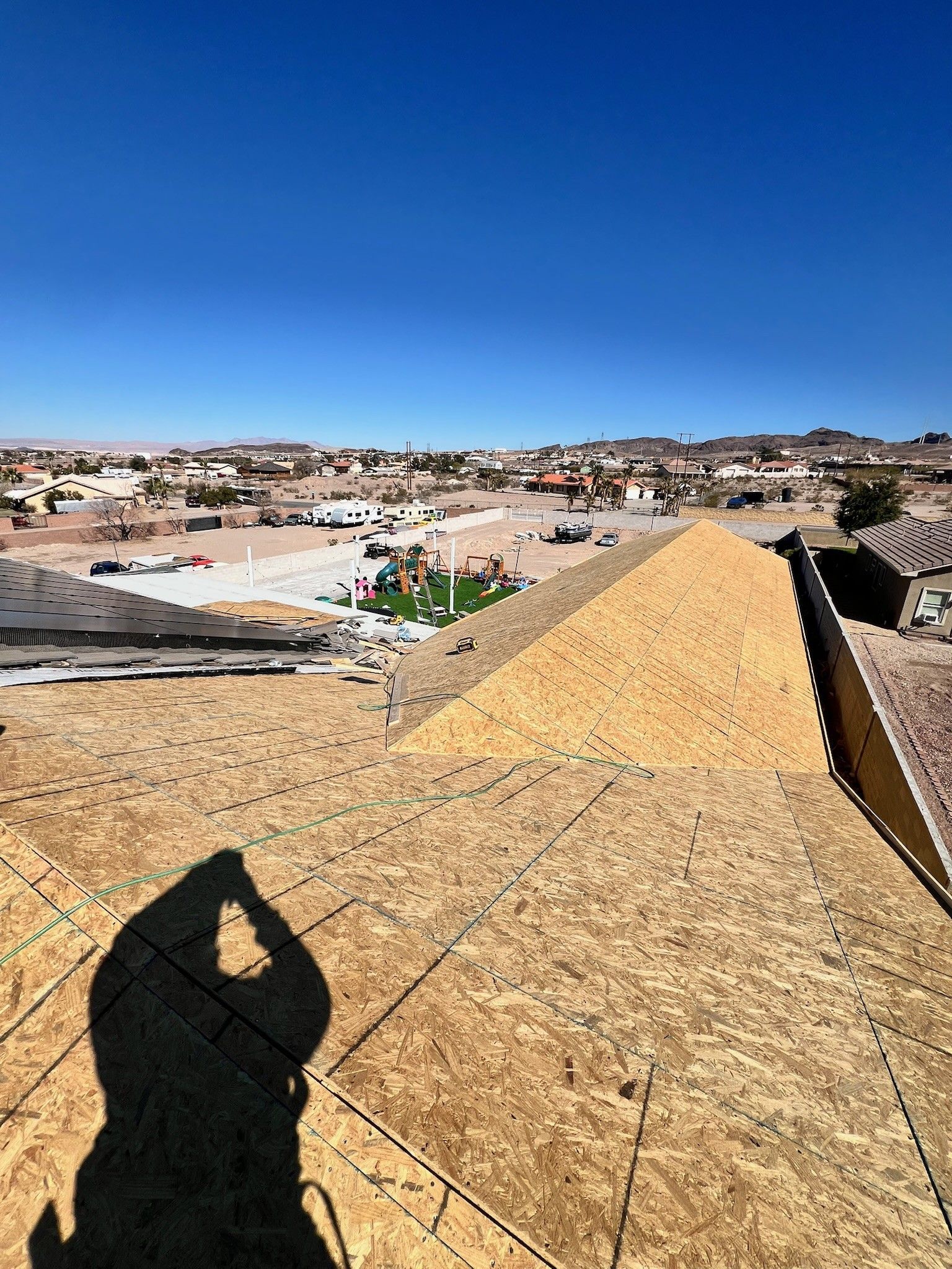 Rooftop under construction overlooking a desert town under a clear blue sky