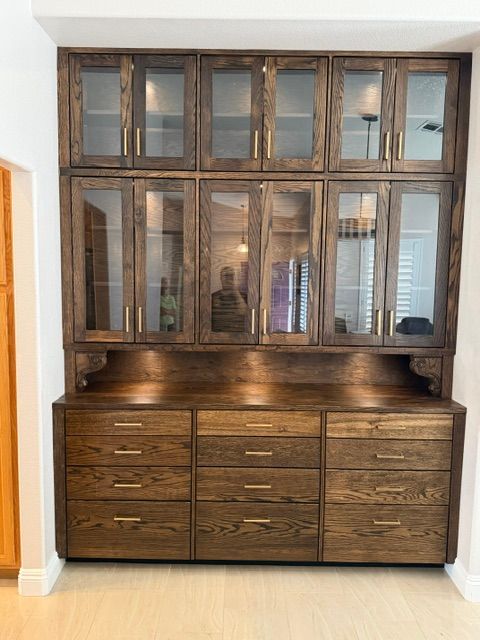 Dark wood hutch with glass cabinet doors and drawers against a white wall