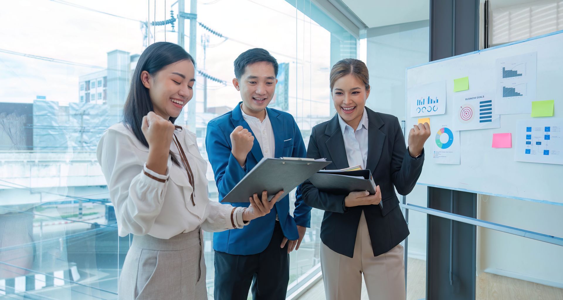 A group of people are standing next to each other in front of a whiteboard.