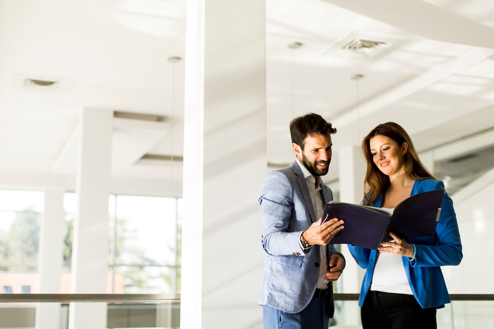 A man and a woman are looking at a clipboard in an office.