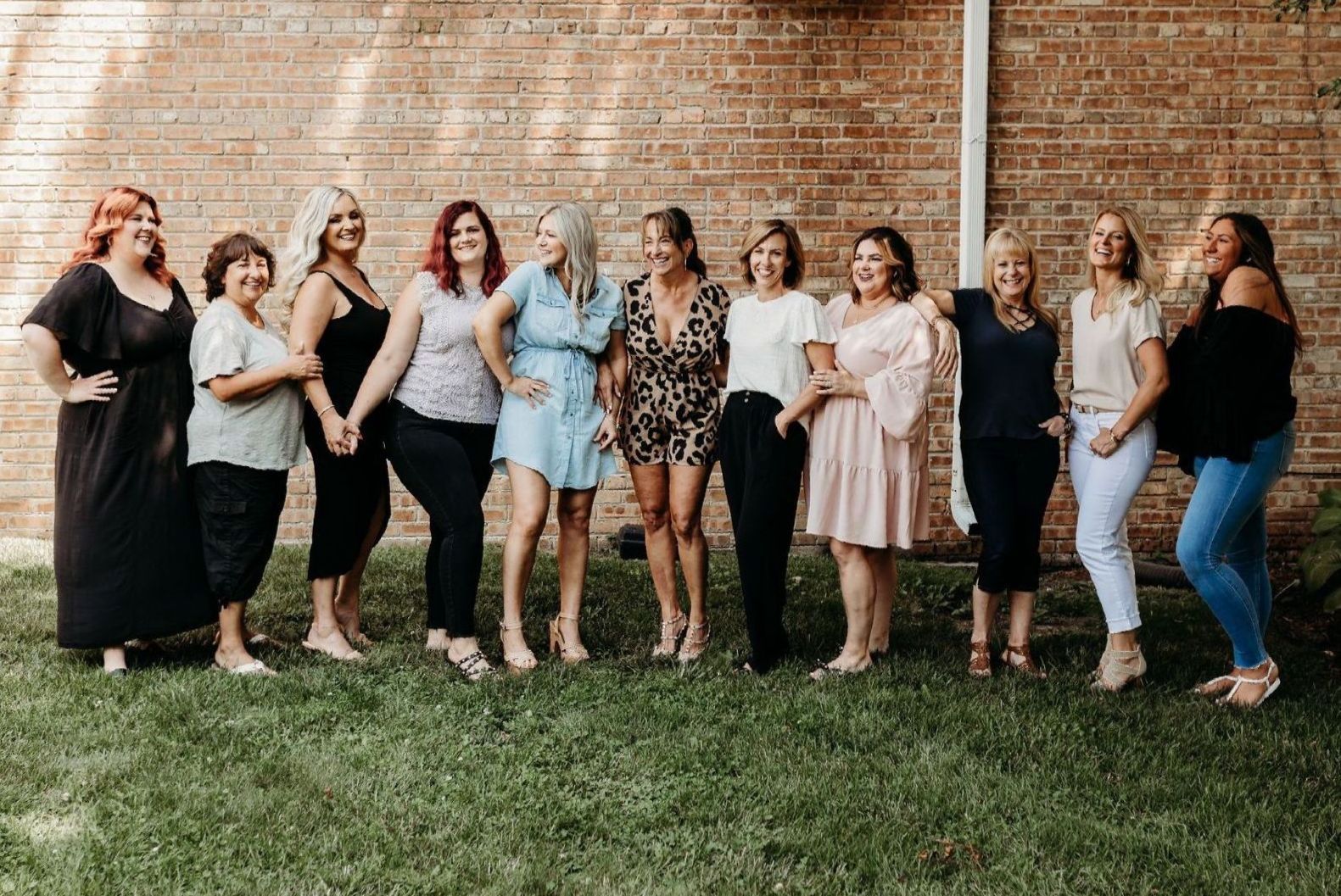 A group of women are standing next to each other in front of a brick wall.