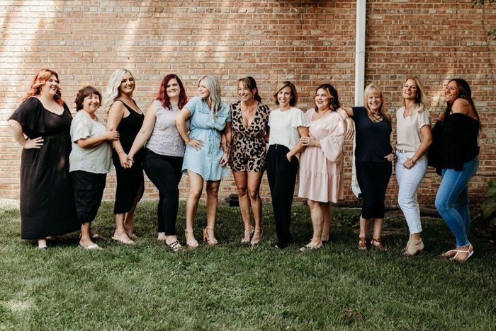 A group of women are standing next to each other in front of a brick wall.