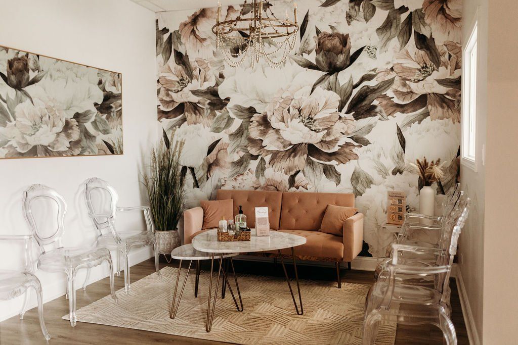 A living room with a couch , table , chairs and a floral wall.