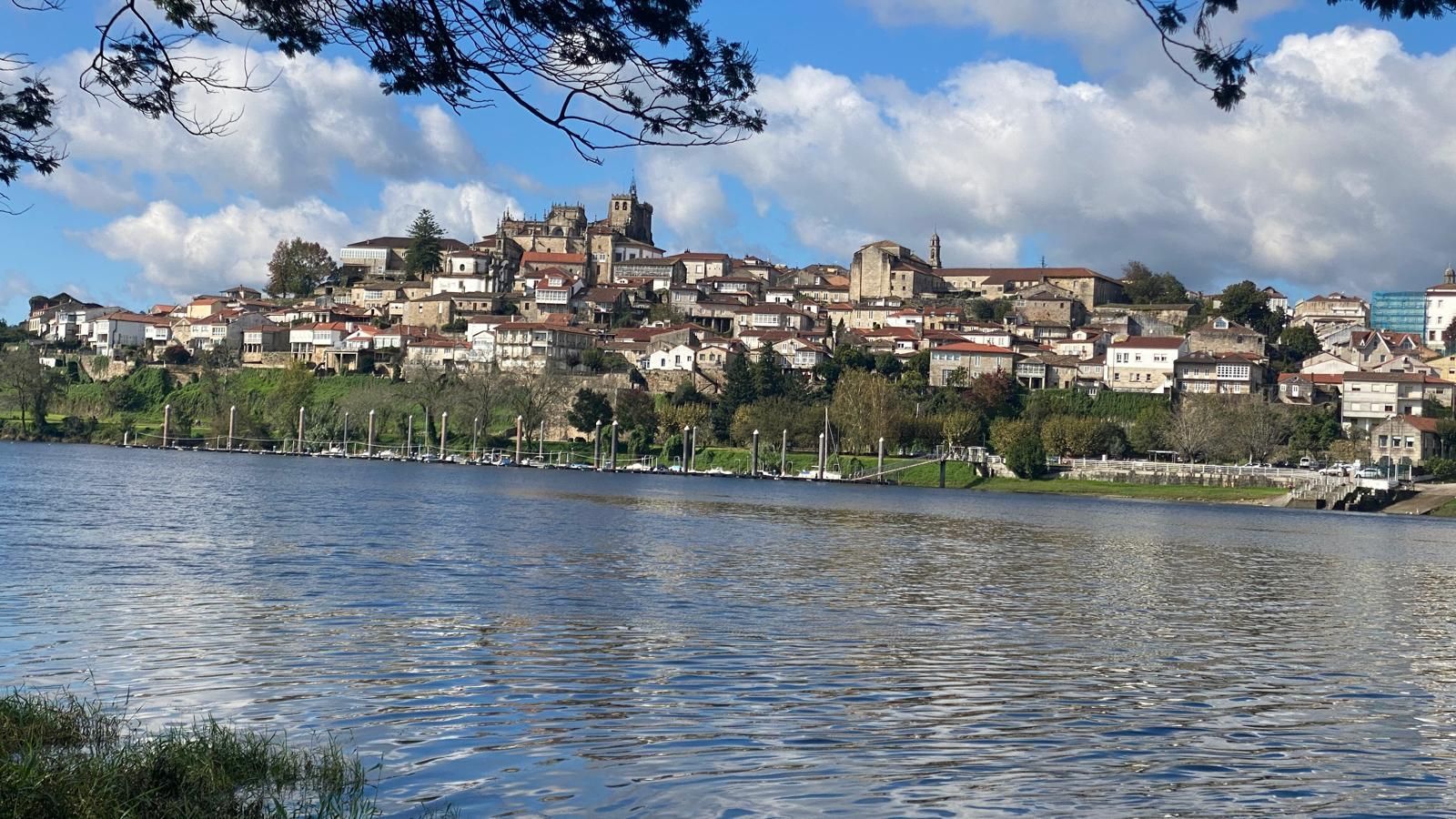 Pueblo en una ladera al otro lado de un río bajo un cielo parcialmente nublado