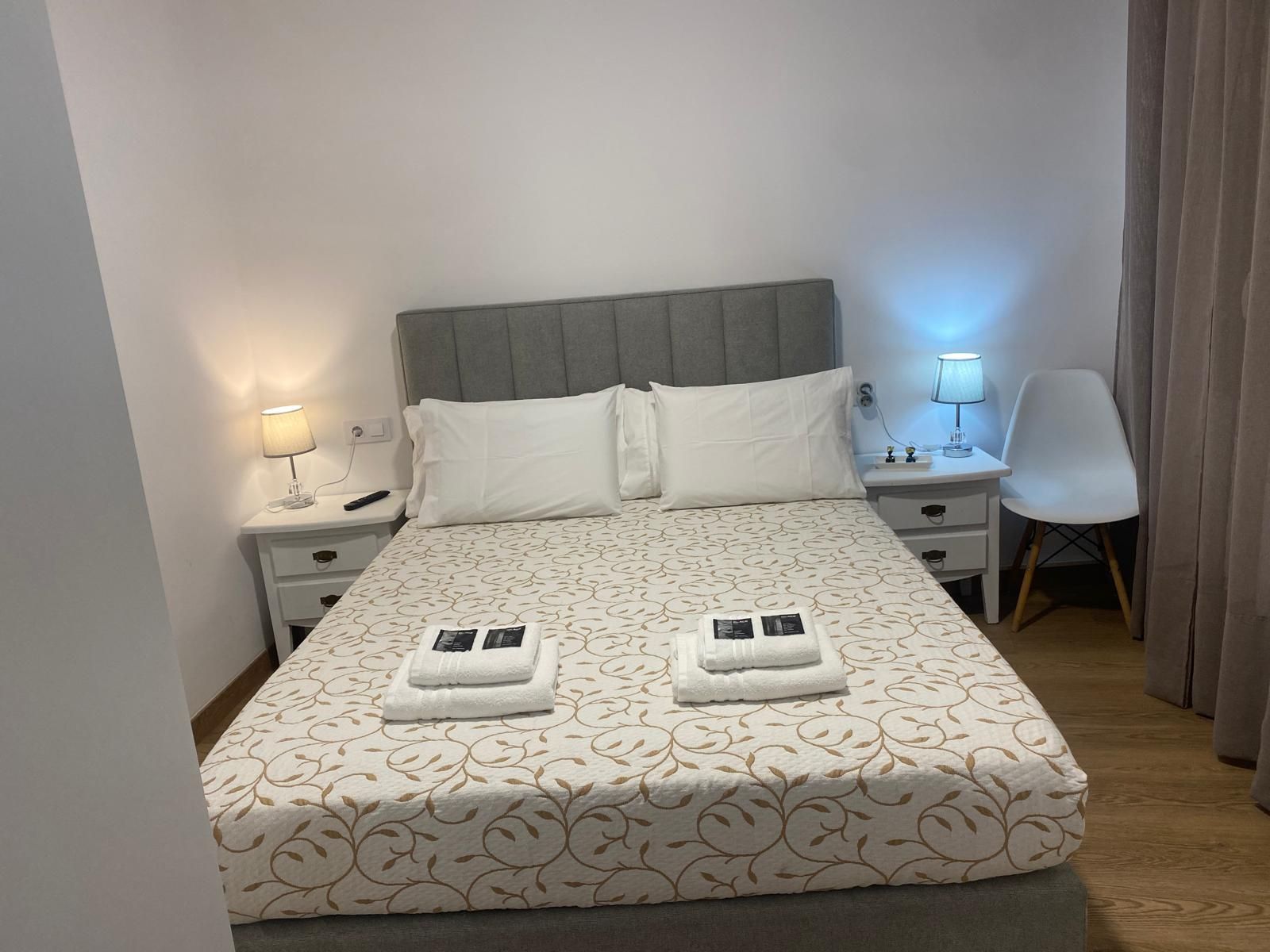 Cama doble bien hecha en un dormitorio minimalista con lámparas de noche y decoración blanca.