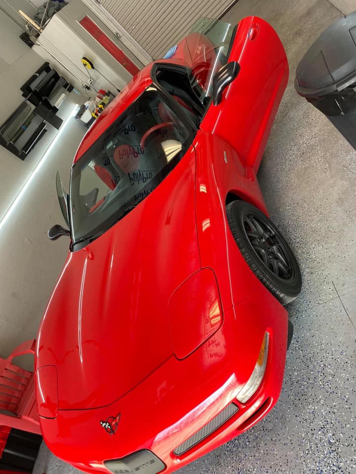 Red sports car parked in a garage, angled front view.