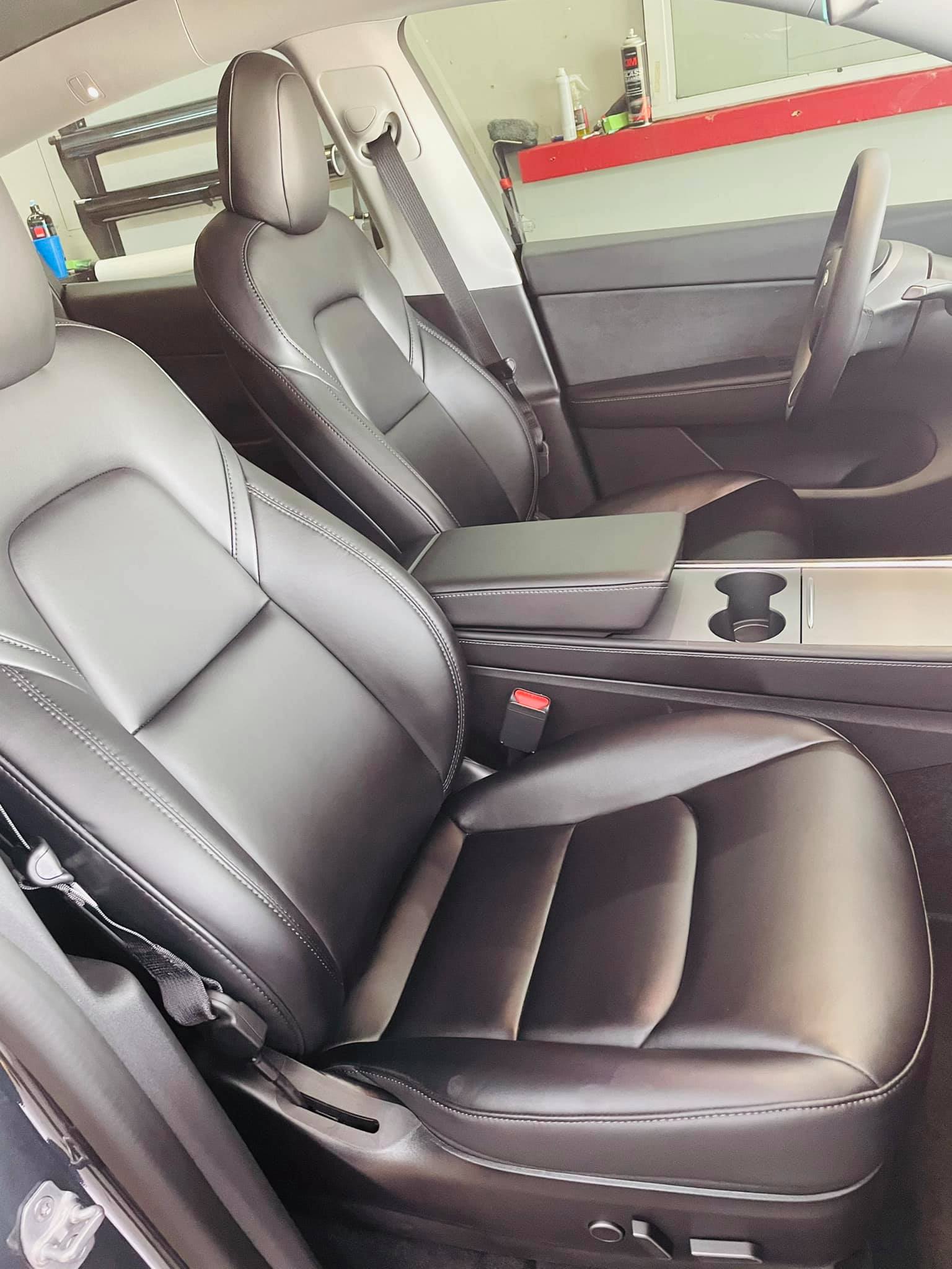 Black leather front seats in a car interior, with center console and cup holders visible