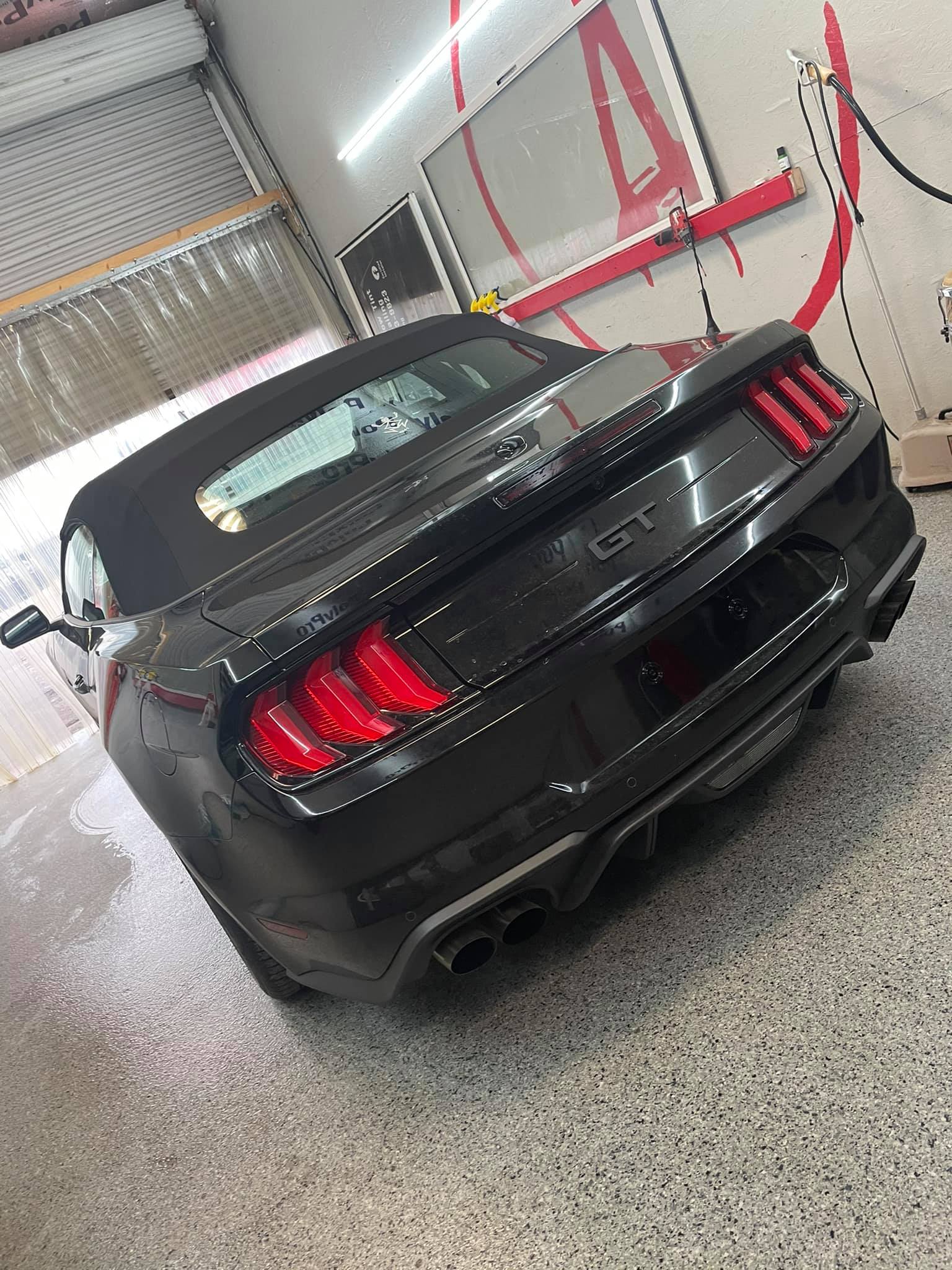 Black sports car with red taillights parked indoors in a garage