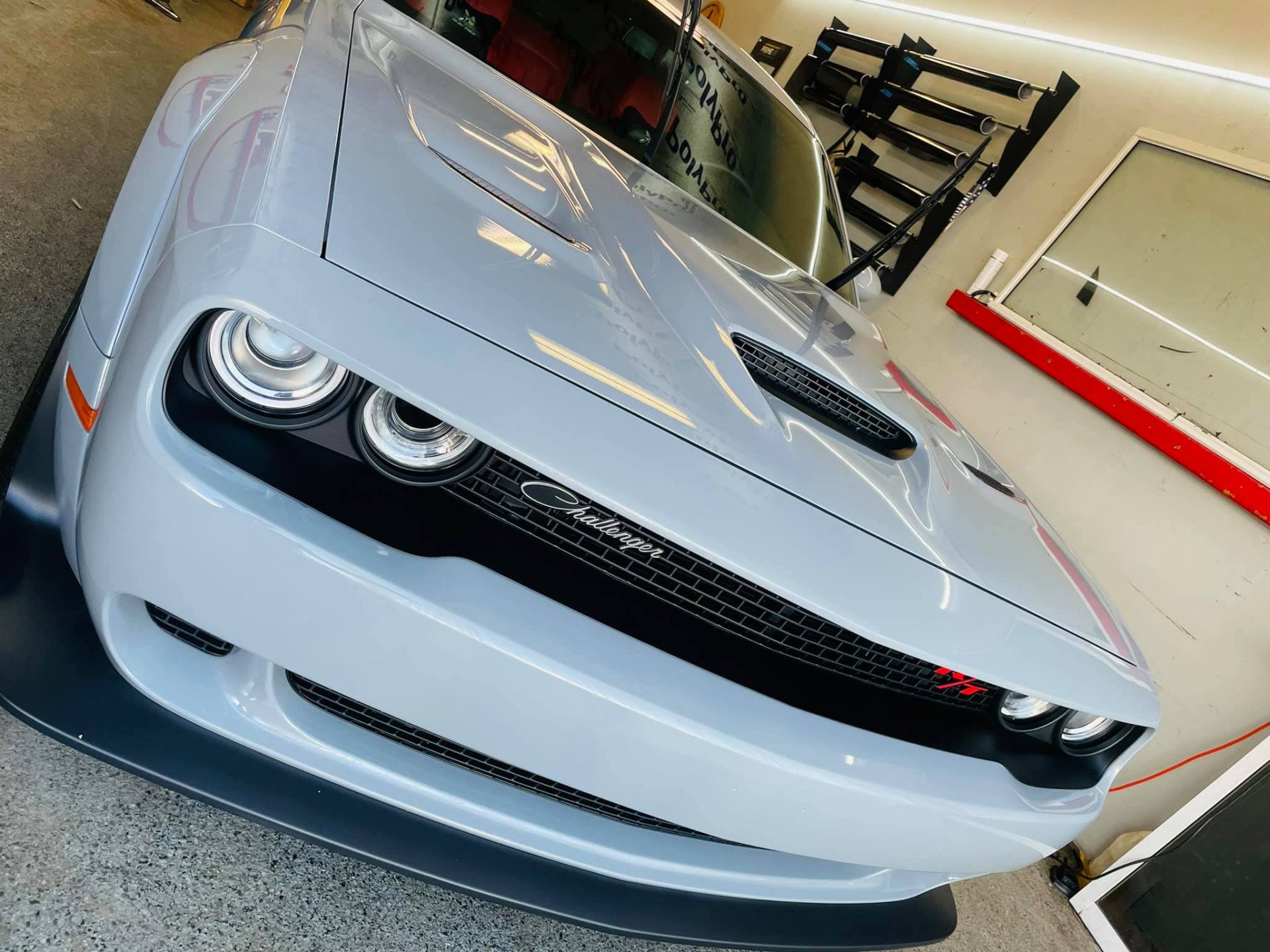 Light blue Dodge Challenger parked in a garage, front view with black grille and round headlights