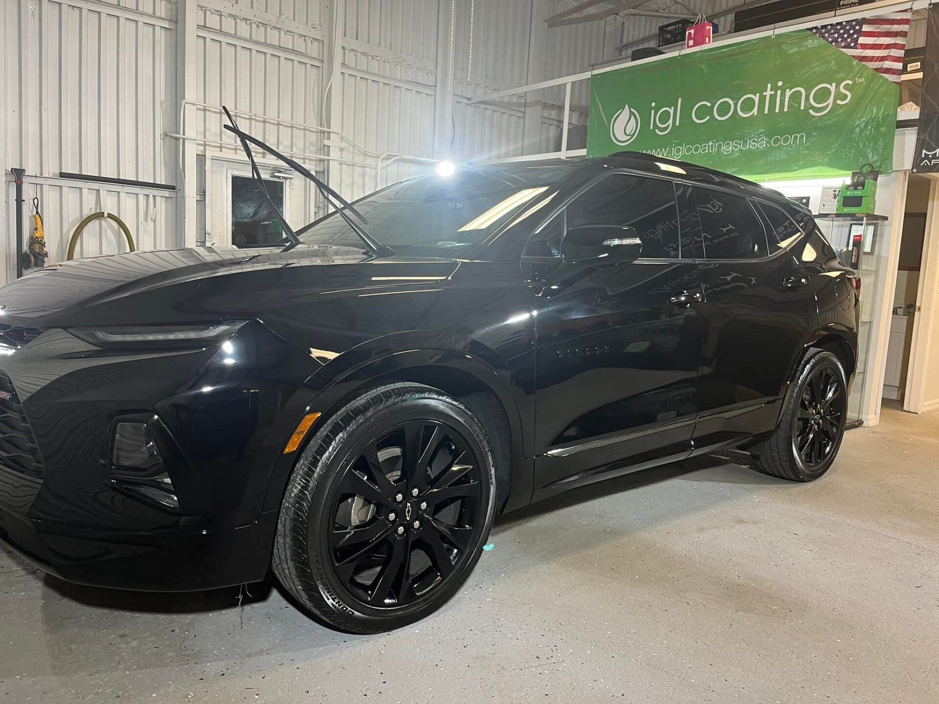 Black SUV parked indoors under bright lights in an auto shop