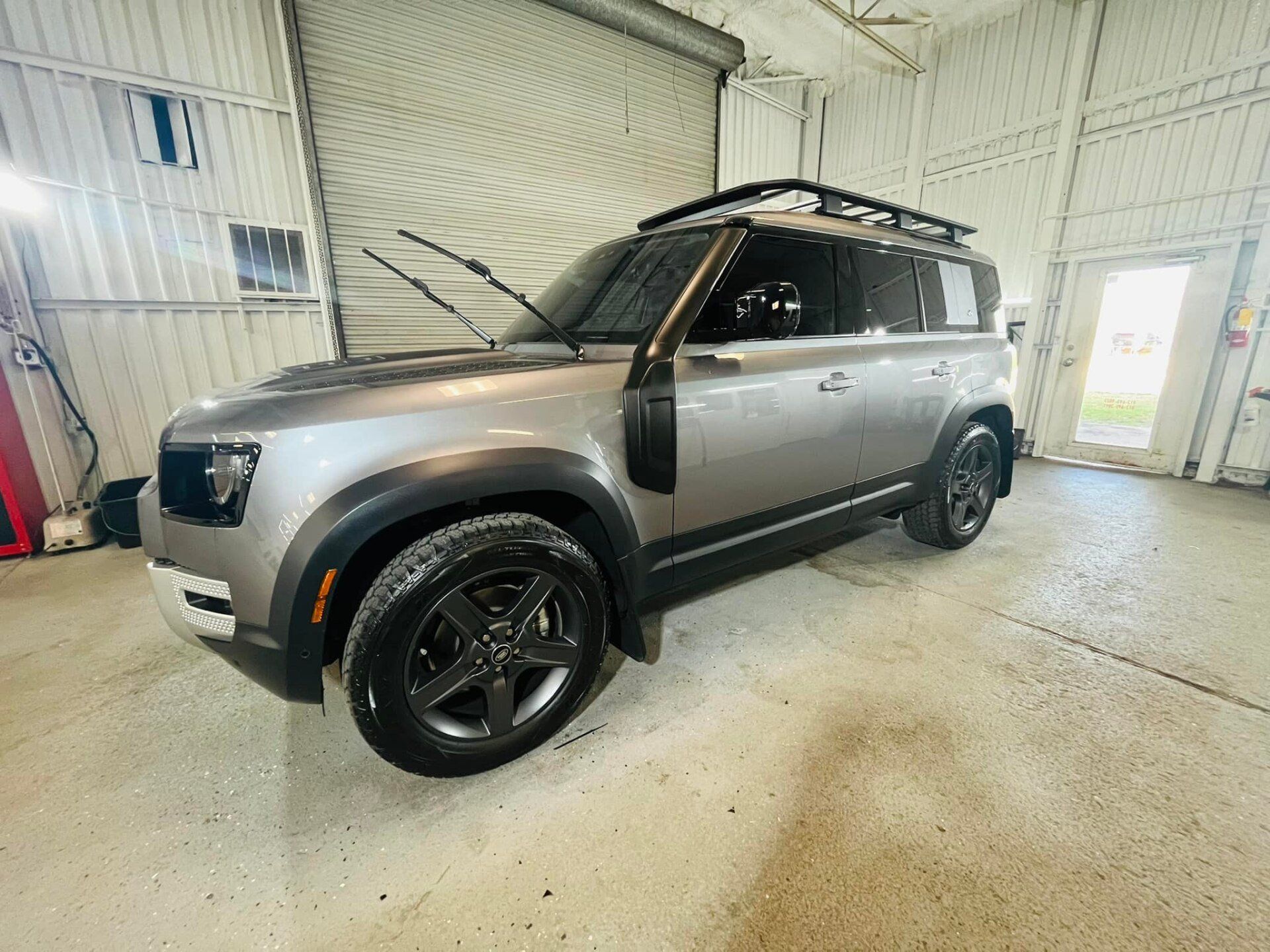Gray SUV with black rims parked inside a bright garage or workshop
