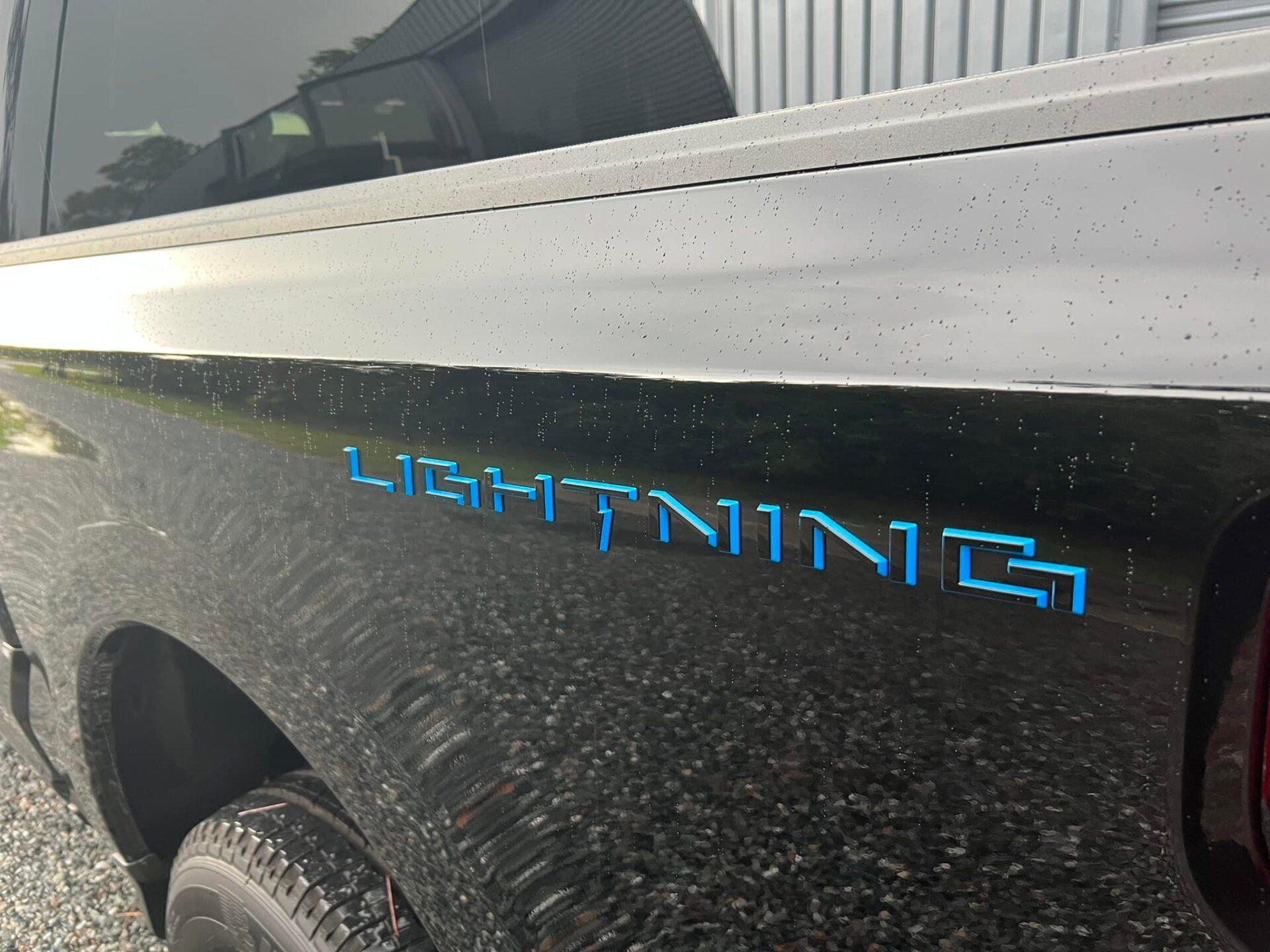 Close-up of a black truck bed with blue “LIGHTNING” decal and silver trim