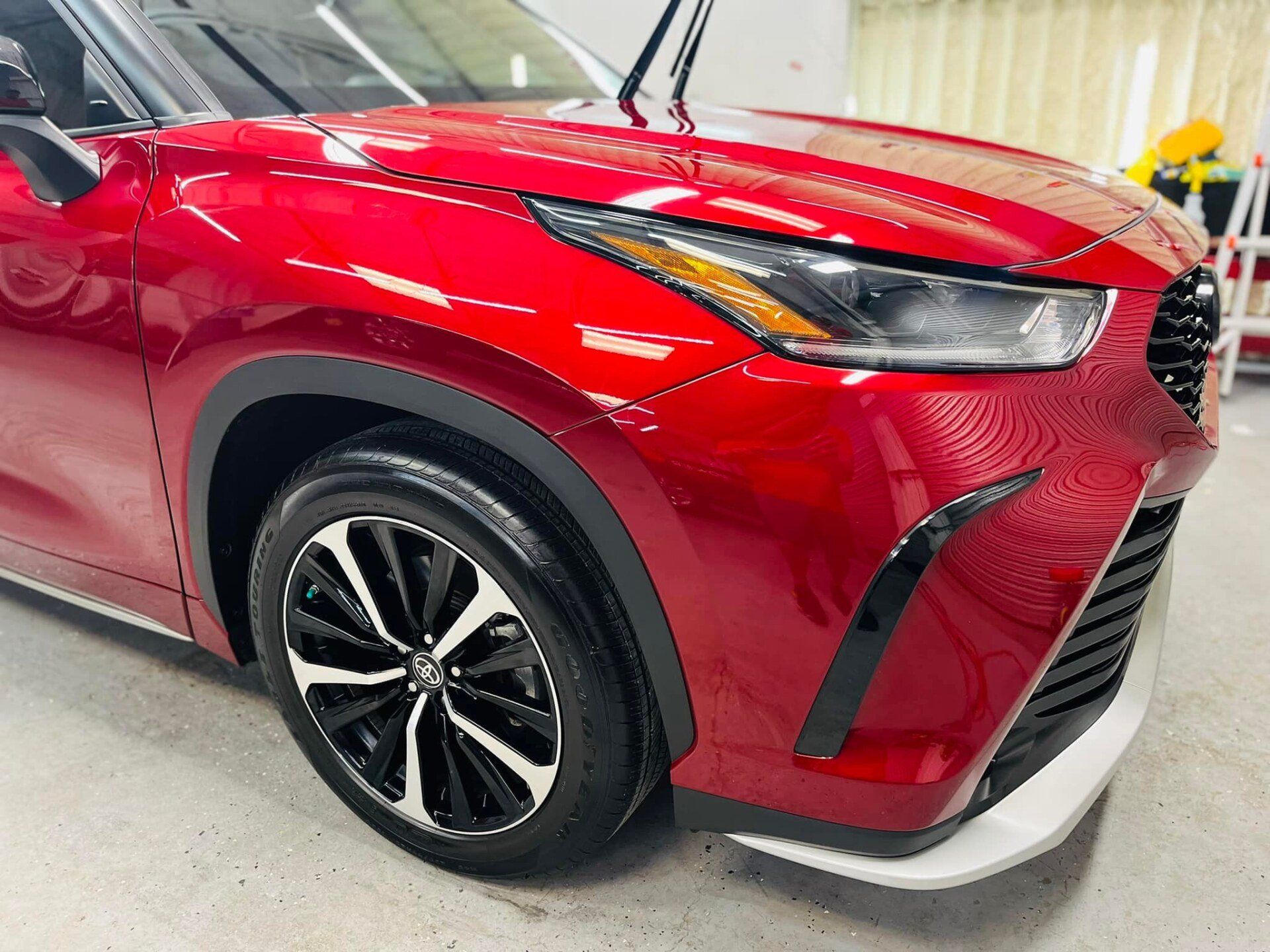 Red compact SUV in a showroom, showing the front-left side with glossy paint and alloy wheel.