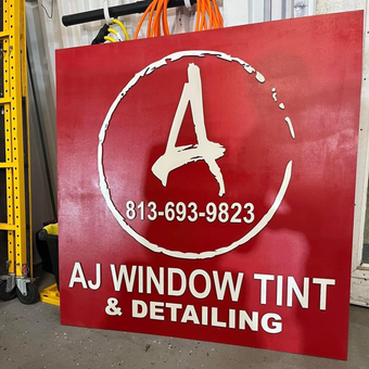 Red sign for AJ Window Tint & Detailing with white logo and phone number 813-693-9823