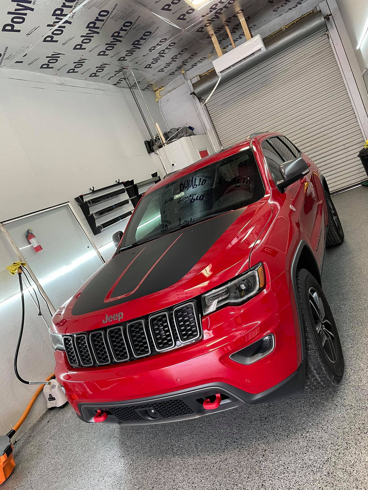 Red SUV in a garage, angled front view, with bright red paint and black grille.