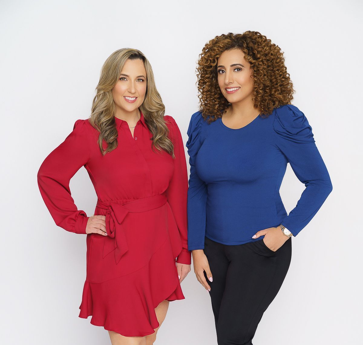 Two women are standing next to each other and one is wearing a red dress and the other is wearing a blue shirt.