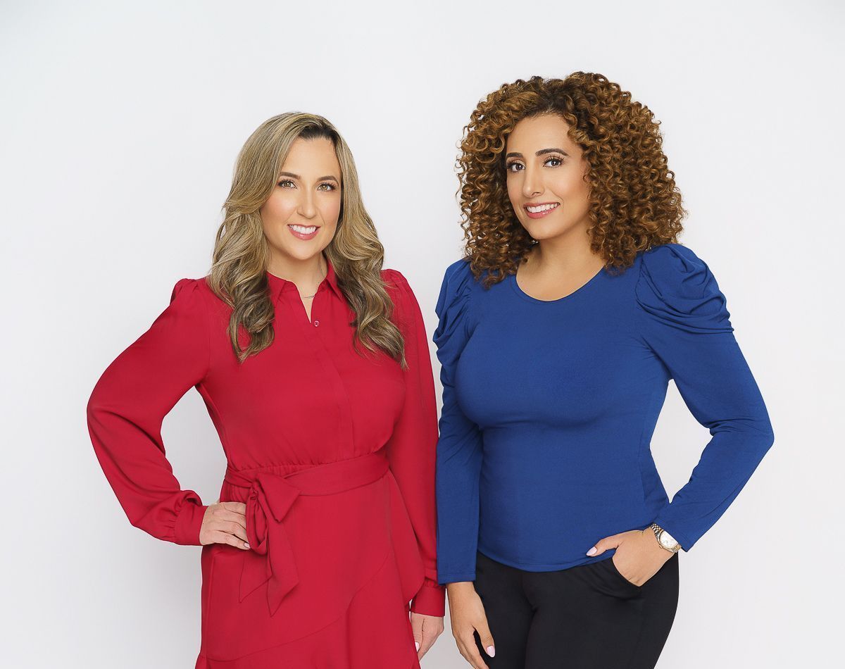 Two women standing next to each other wearing red and blue shirts.
