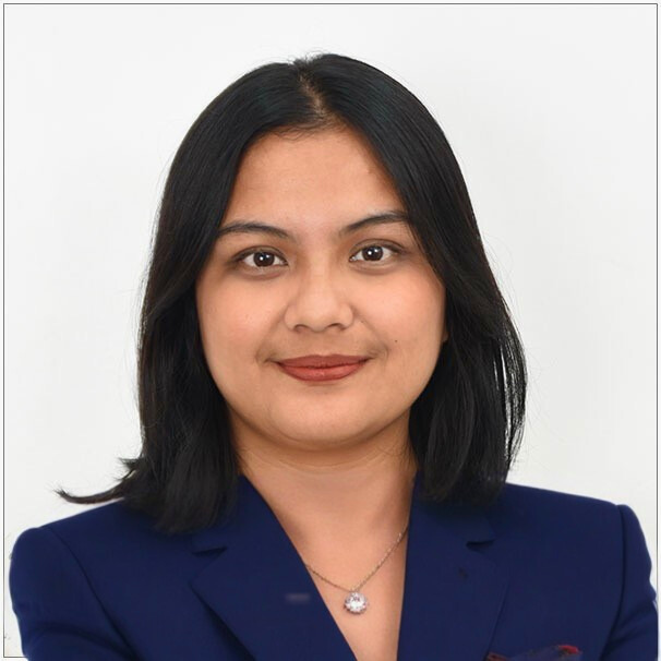 A woman wearing a blue jacket and a necklace smiles for the camera